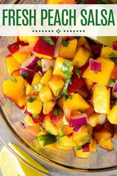 a glass bowl filled with chopped fruit and garnished with cilantro, limes, and onions