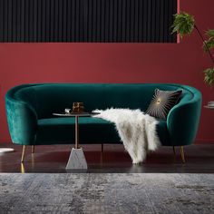 a green velvet couch in a living room with red walls and rugs on the floor