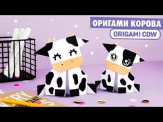 two paper cows sitting next to each other on a purple surface with confetti