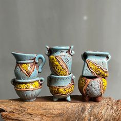 three ceramic vases sitting on top of a piece of driftwood next to each other