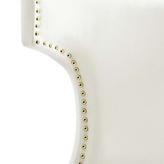 an upholstered white chair with gold studded trimmings on the back