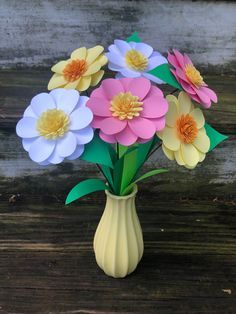 a vase filled with paper flowers on top of a wooden table