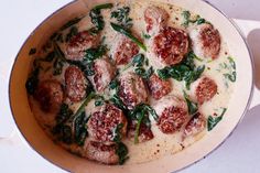 a pan filled with meatballs and spinach on top of a white countertop