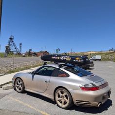 a silver sports car parked on the side of the road with luggage strapped to it's roof