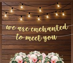 two vases filled with flowers sitting on top of a table next to a sign that says, we are enchanted to meet you