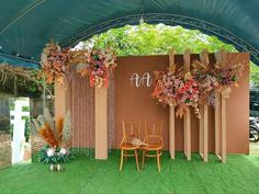 an outdoor wedding setup with chairs and flowers on the back wall, surrounded by greenery