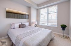 a white bed sitting under a window in a bedroom