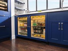 an open refrigerator in a kitchen with blue cabinets and wood flooring on the side