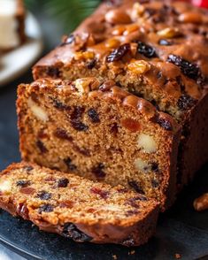 a loaf of fruit bread with nuts and raisins on the side, sitting on a plate