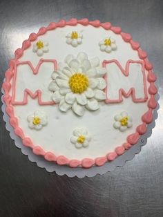 a cake decorated with flowers and the word mom written in white frosting on a silver surface