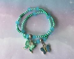 This is a cute little stretch bracelet. It wraps twice and even has some iridescent green beads. It features silver-toned accents, and two butterfly charms in teal and blue. It's about 6.75 inches. Sizing guide: *Measure the width/circumference of your wrist. *Add 1/4 to 1/2 inch (depending on how loose you like to wear your bracelets). *This is your size. --For example: if your wrist measures 7 inches, add 1/4 to 1/2 inch. You would select a size 7.25 (7-1/4) or 7.50 (7-1/2). Green Adjustable Jewelry With Butterfly Charm, Adjustable Silver Beaded Bracelet With Butterfly Charm, Butterfly Stretch, Stack Bracelet, Iridescent Green, Bronze Ring, Green Beads, Green Quartz, Butterfly Charm