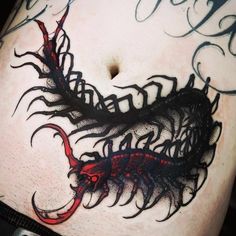 an artistic tattoo design on the side of a woman's stomach with black and red ink