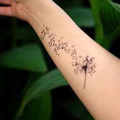 a woman's arm with a dandelion tattoo that reads, music notes