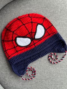 a crocheted spiderman hat with candy canes on the side, sitting on a chair