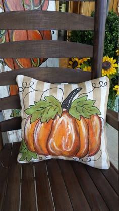 an orange pumpkin pillow sitting on top of a wooden chair