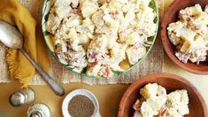 three bowls filled with potato salad on top of a table next to two spoons