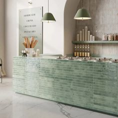 a kitchen with green tile counter tops and hanging lights over the bar area in front of it