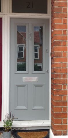 the front door is painted gray and has two potted plants on the side walk