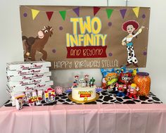 two infinnty birthday party table with cake, candy and other items on it