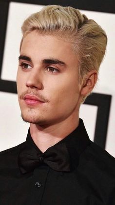 a man with blonde hair wearing a black shirt and bow tie