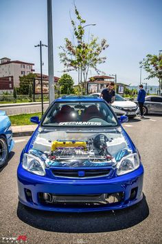 a blue car parked in a parking lot next to other cars