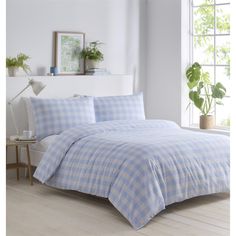 a blue and white checkered comforter set on a bed in front of a window