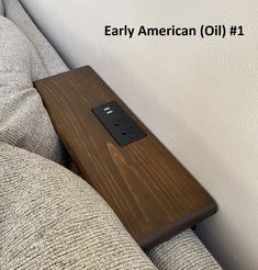 a remote control sitting on top of a wooden table next to a gray couch with the words, early american oil 1