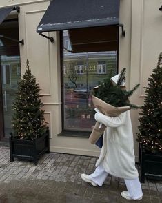 a person dressed as a teddy bear carrying a christmas tree in front of a store