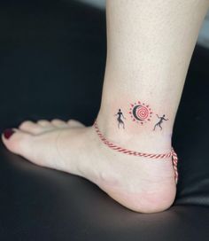 a woman's foot with a small tattoo on the ankle that has three people and a spiral design