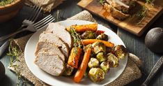 a white plate topped with meat and veggies on top of a wooden table