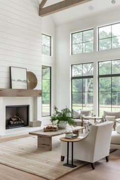 a living room filled with furniture and a fire place in front of two large windows