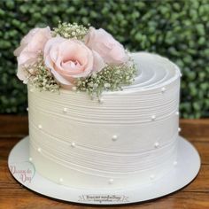 there is a white cake with pink flowers on top