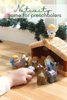 a child playing with nativity game for preschiolers on the table in front of christmas tree