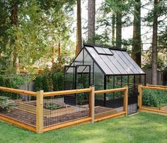 a small greenhouse in the middle of some grass