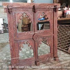 an ornately carved wooden cabinet with mirrors on the front and back doors, in a shop