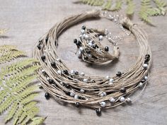 a close up of a bunch of necklaces on a table with plants and leaves