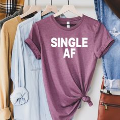 "Single AF Shirt - Single Shirt - Single As - Valentine Shirt - Hate Love Shirt - Custom Shirts - Sarcastic shirts - Single and shirt - gift Single AF THIS LISTING IS FOR ONE SHIRT 1. Chose size and color of shirt - add to cart 2. Go back choose more sizes/colors as needed If you have any questions, feel free to ask. Adult Unisex Triblend short sleeved Crew Neck. 50% Poly 25% Combed Ring-Spun Cotton 25% Rayon This shirt is Unisex so for a female, it is a little loose - if you like them \"FORM FI Cute Fitted Purple T-shirt, Casual Fitted Shirt With Funny Print, Casual Tops With Funny Text For Gifts, Casual Shirt With Funny Text As Gift, Casual Letter Print Tops As Gift, Casual Relaxed Fit Tops For Gifts, Casual Cotton Shirt As Gift, Casual Relaxed Fit Tops As A Gift, Casual Tops With Funny Print For Gifts