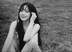 black and white photograph of a woman sitting on the grass talking on her cell phone