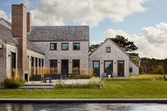 a large house sitting on top of a lush green field next to a body of water