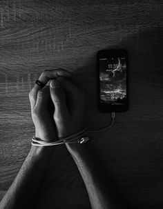 a person holding their hand on top of a cell phone next to a string wrapped around his wrist