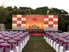 an outdoor ceremony setup with white chairs and pink sashes, decorated with flowers and lights