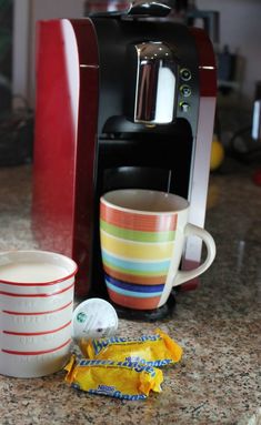 a coffee maker sitting on top of a counter next to a cup