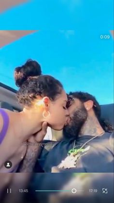 a man and woman kissing in the back seat of a car with blue sky behind them