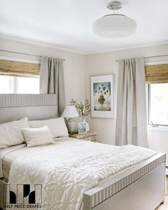 a white bed sitting in a bedroom next to two windows