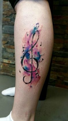 watercolor tattoo on the leg of a woman's legs with music notes painted on it