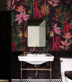 a bathroom with floral wallpaper and black tiled walls, along with a white sink