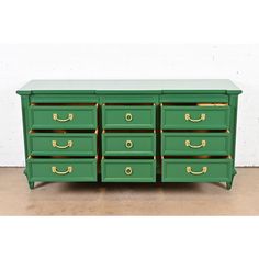 a green dresser with gold handles and drawers on the bottom, in front of a white wall