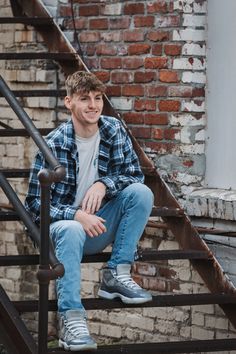 a young man sitting on top of a set of stairs next to a brick building