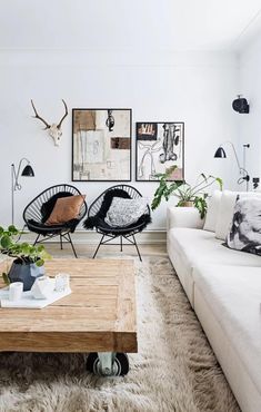 a living room filled with furniture and plants on top of a wooden table in front of a white wall