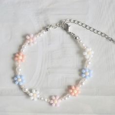 a white bracelet with pastel colored beads and silver chains on a white surface,